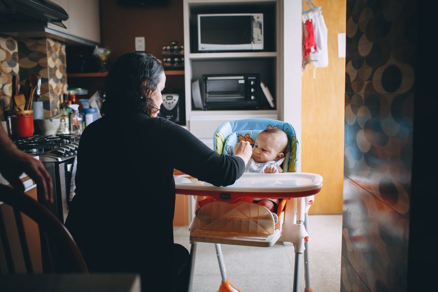 A mother feeding her baby in a kitchen